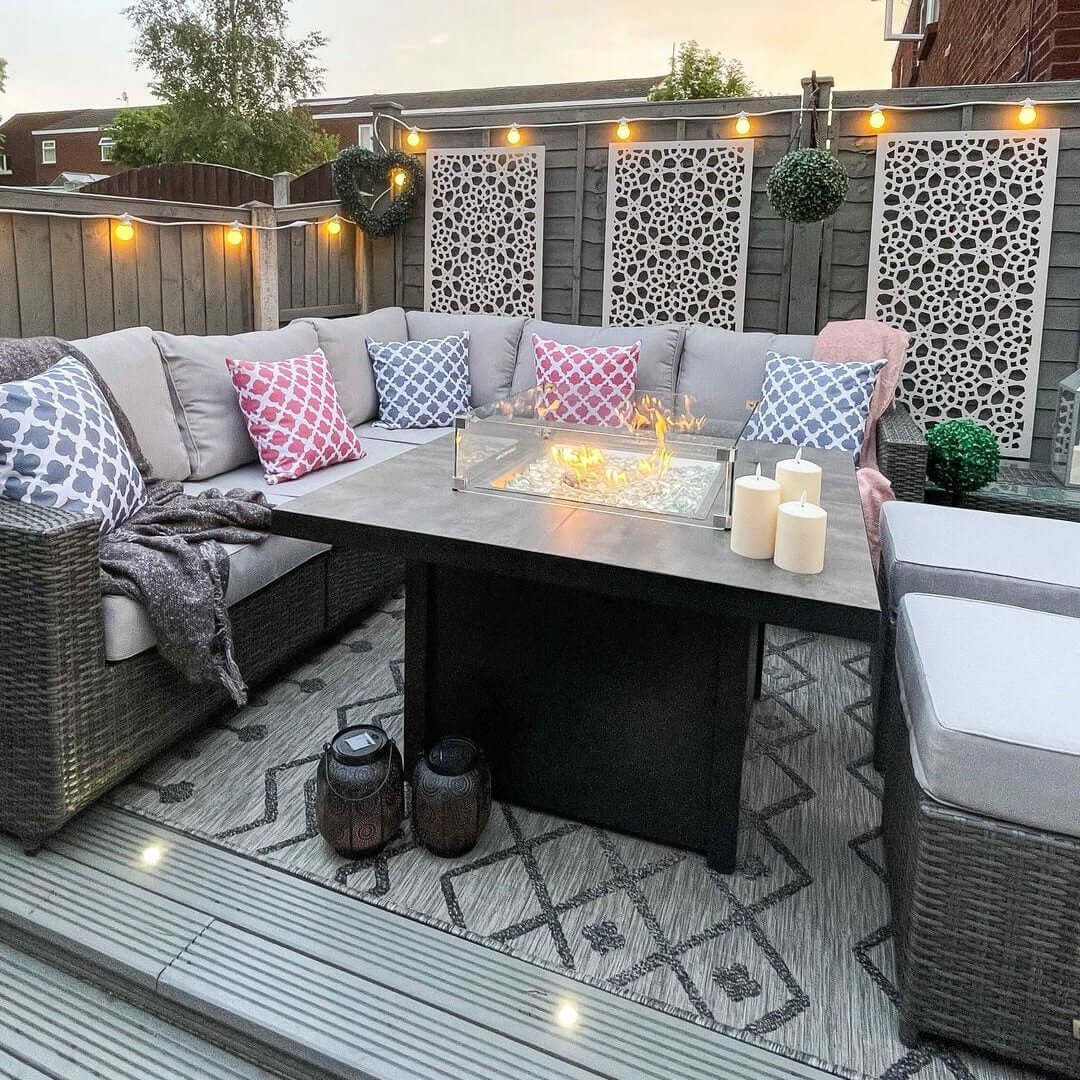 Cozy outdoor seating area with patterned cushions, fire table, and decorative lighting for a stylish ambiance.
