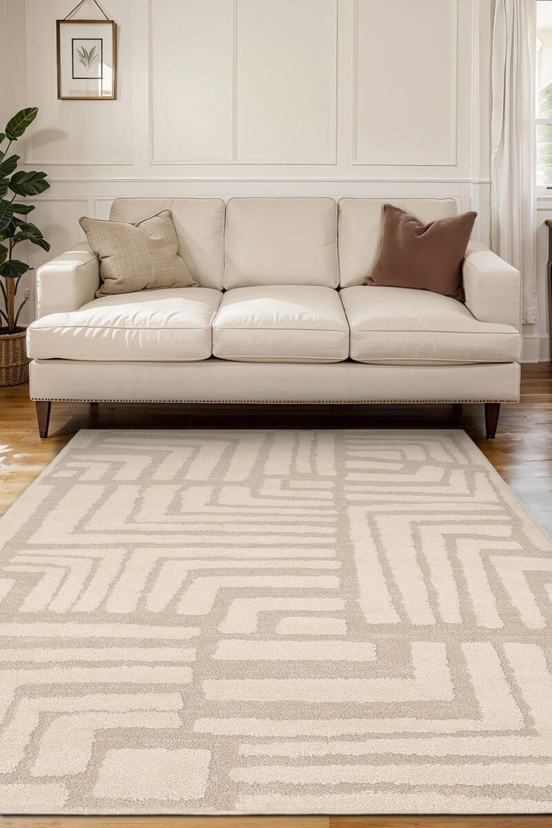 Ava Pave Wave Illusion Rug in cream tones, featuring an abstract design, placed in a modern living room with a beige sofa.