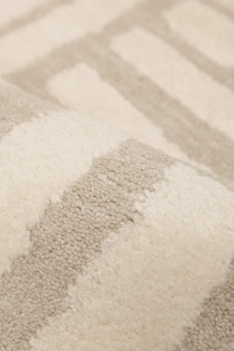Close-up of the Ava Pave Wave Illusion Rug showcasing soft cream and grey abstract striped design.