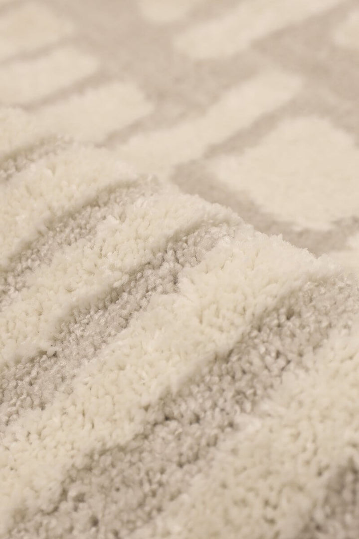 Close-up of the Ava Pave Wave Illusion Rug showcasing its cream abstract design and plush high-low pile texture.