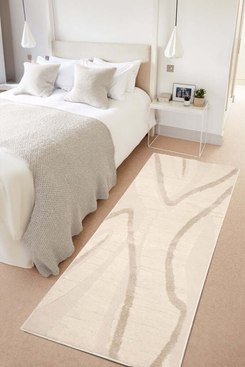 Ava Pave Wave Illusion Rug in cream tones displayed in a cozy bedroom with a bed and decorative pillows.