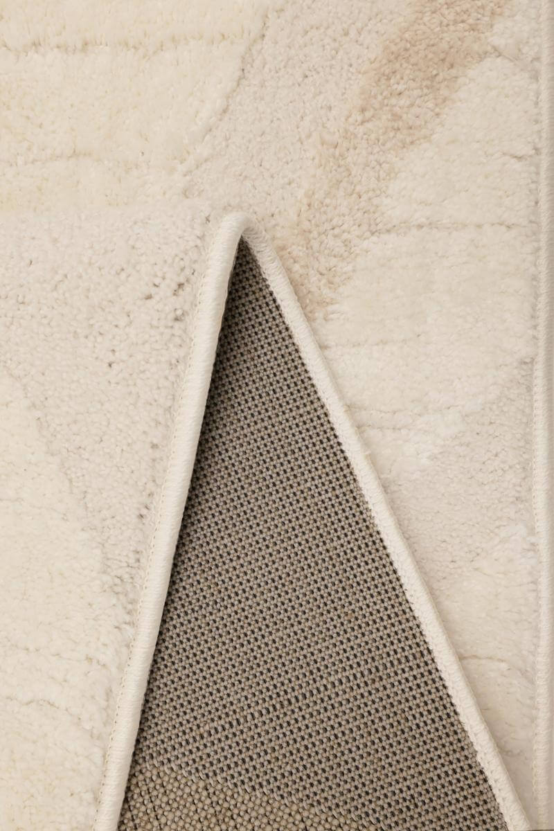 Close-up of Ava Pave Wave Illusion Rug's cream abstract texture and backing, highlighting its soft and durable fabric.