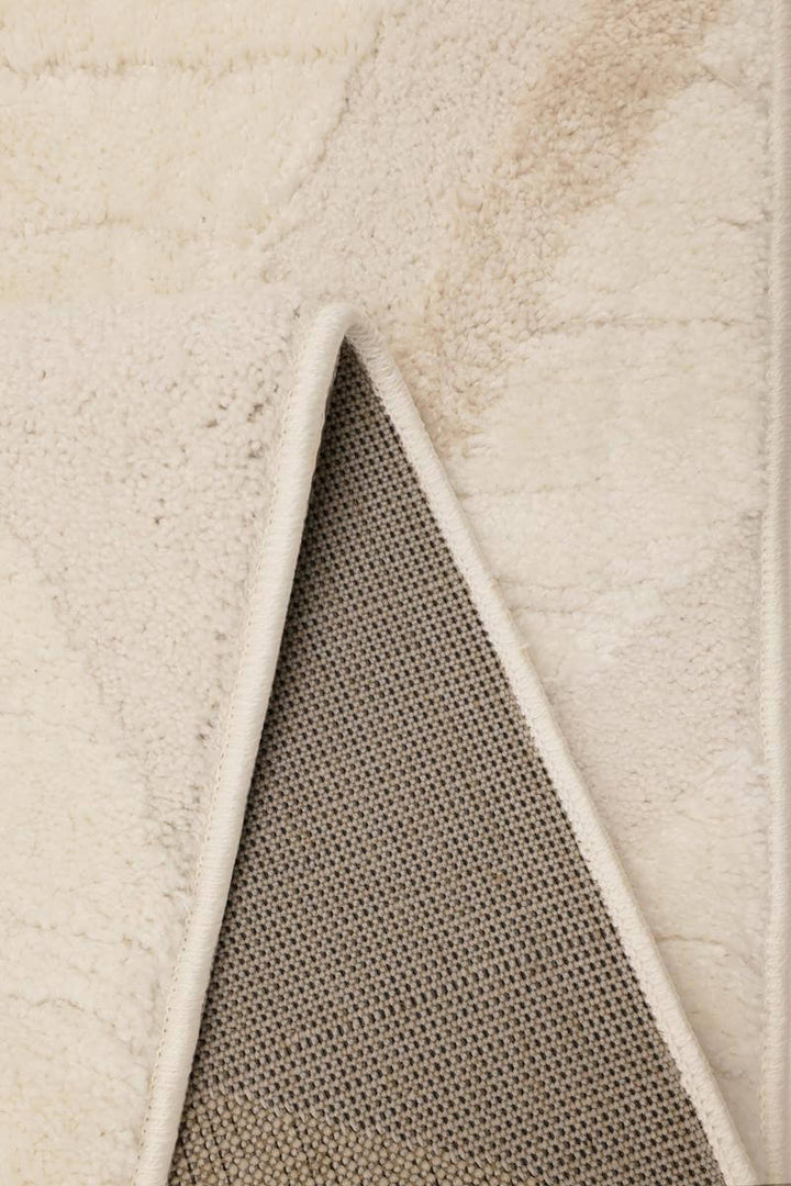 Close-up of Ava Pave Wave Illusion Rug's cream abstract texture and backing, highlighting its soft and durable fabric.