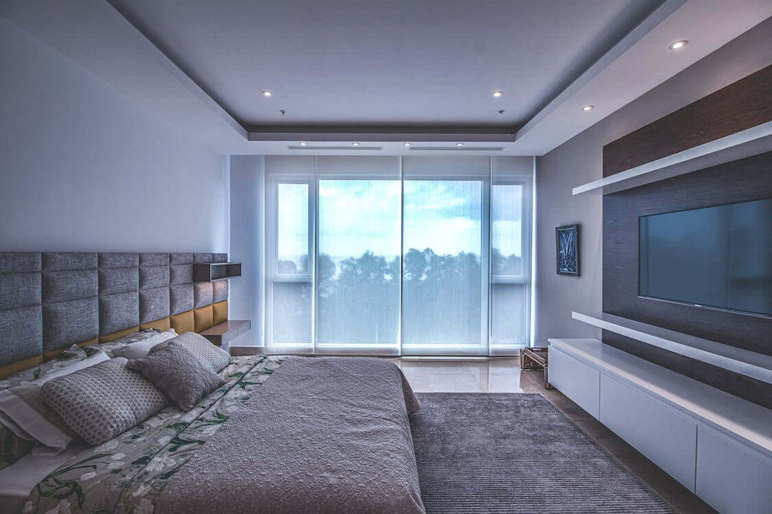 Modern bedroom with a large window, stylish bed, and minimalist decor, showcasing elegance and comfort.