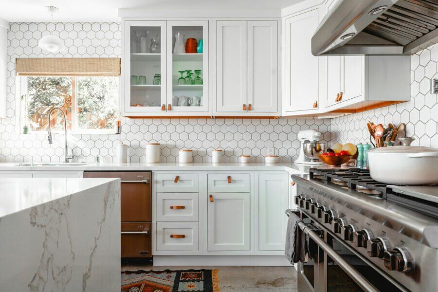 Bright and modern kitchen with white cabinets, hexagon backsplash, and stainless steel appliances.
