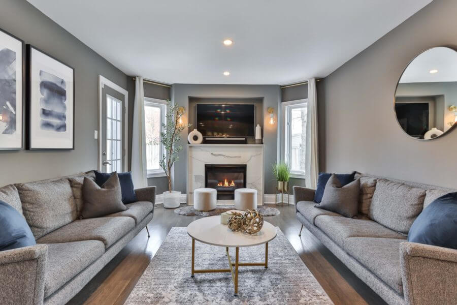 Cozy contemporary living room featuring gray sofas, a round coffee table, and a fireplace ambiance.