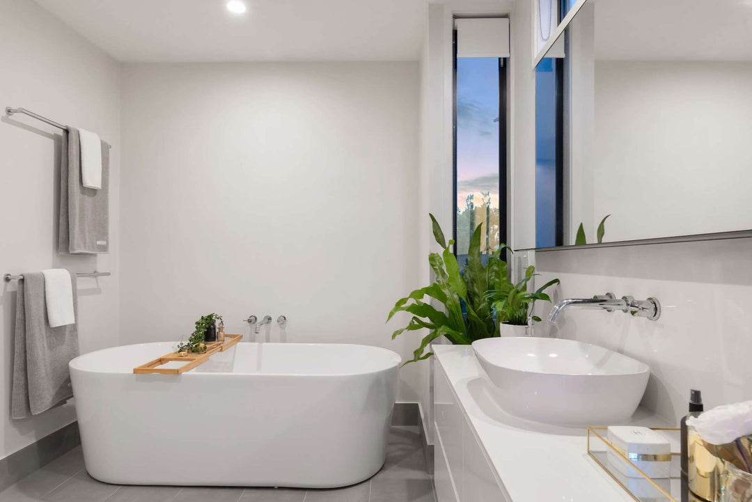 Modern bathroom featuring a freestanding tub, stylish sink, and greenery, designed for relaxation and elegance.