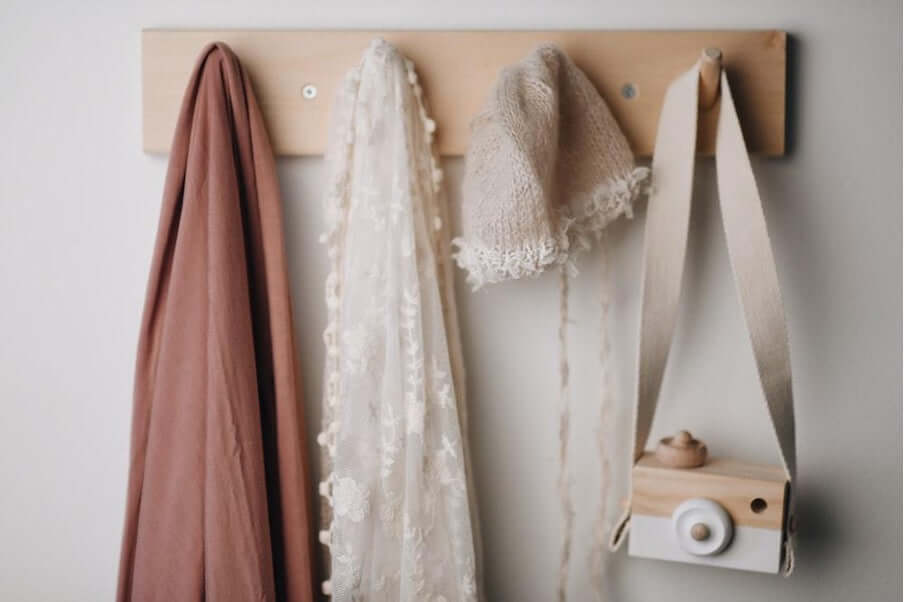 Stylish wall-mounted rack with scarves, a knitted hat, and a vintage-inspired camera prop.