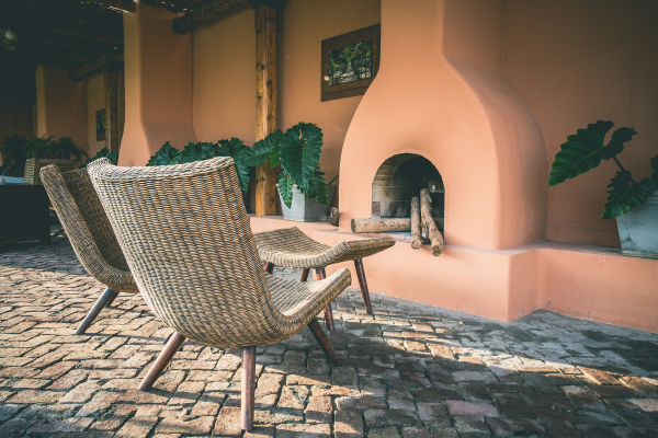 An outdoor fireplace with two wicker chairs