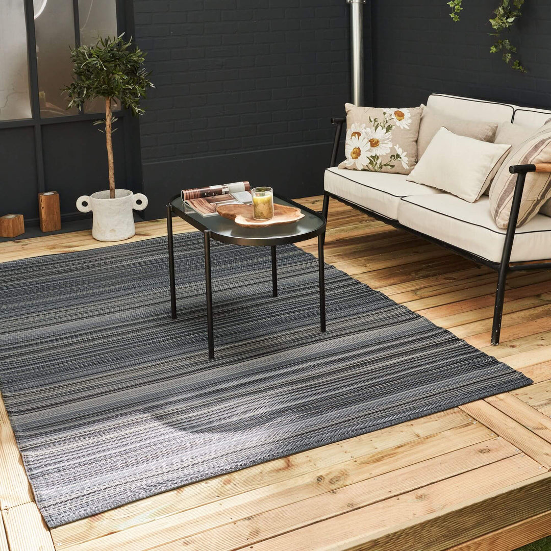 Modern outdoor space with dark grey striped geometric rug and stylish seating arrangement.