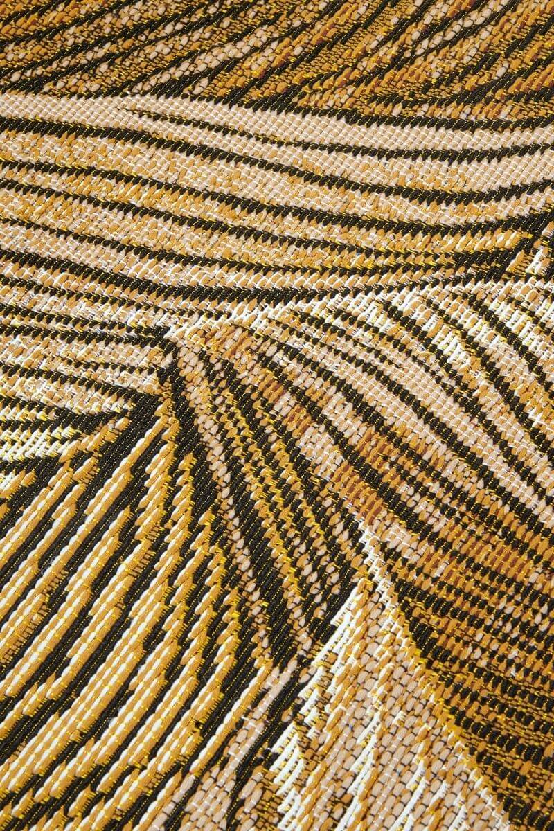 Close-up of a textured fabric with a pattern of lines in gold, black, and beige.
