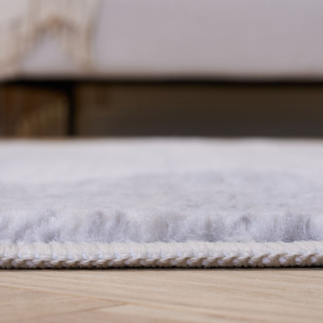 Close-up of a textured white rug on a wooden floor