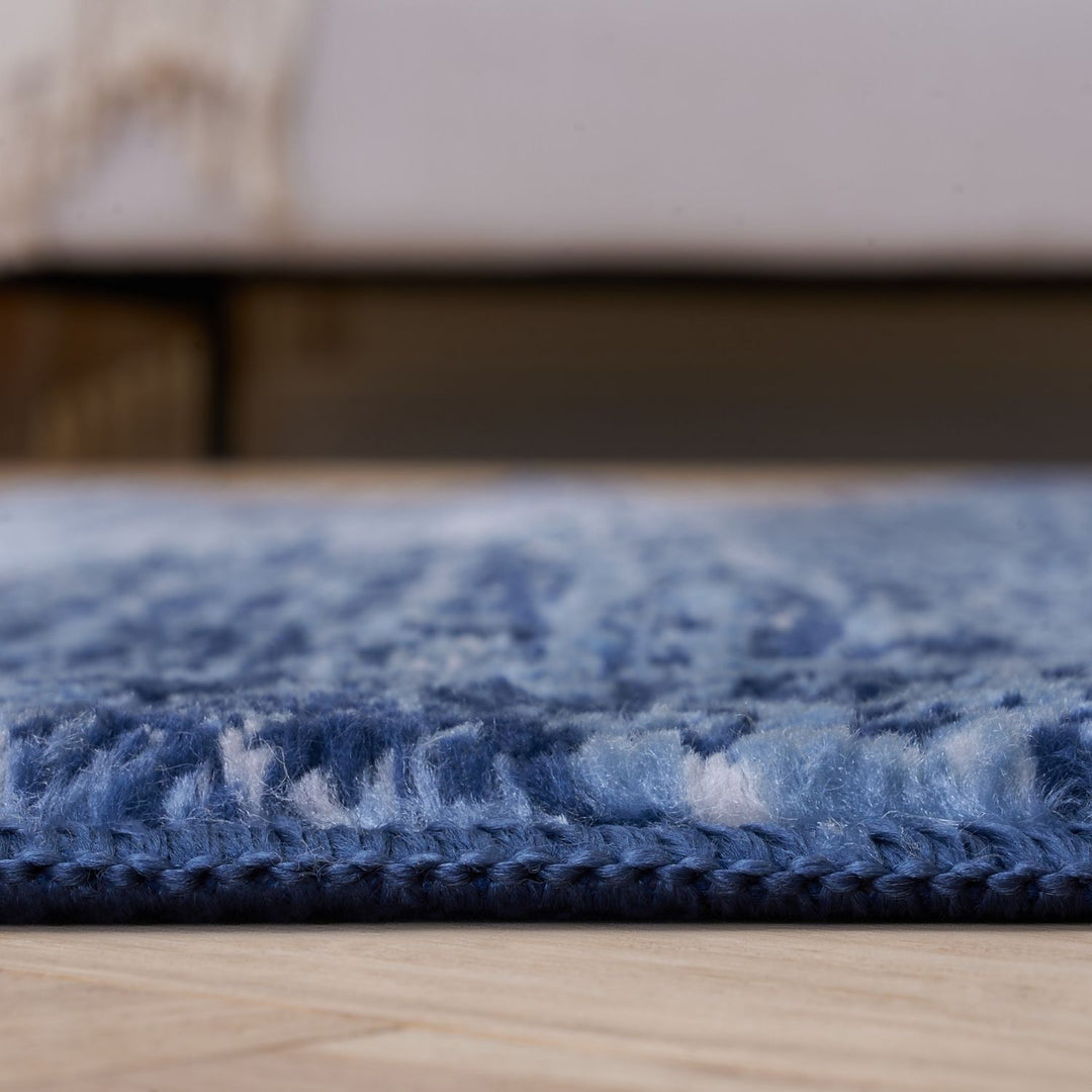 Close-up of a blue textured rug on a wooden floor.