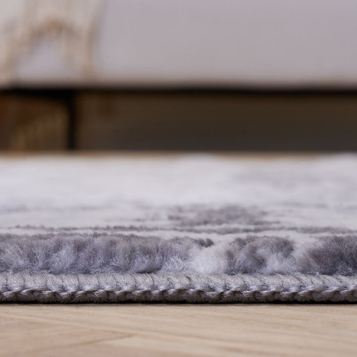 Gray textured rug on a wooden floor with a blurred background