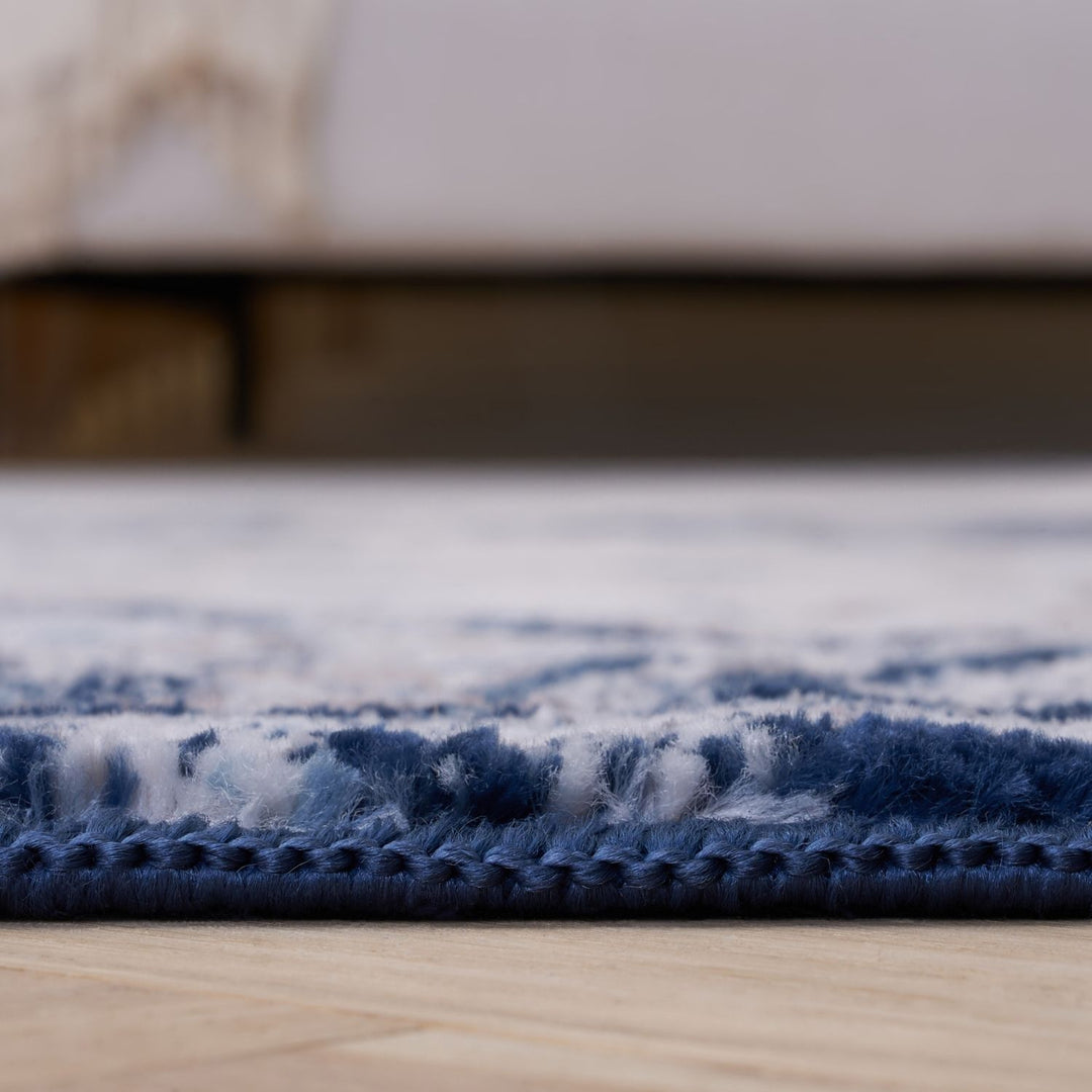 Close-up of a blue and white patterned rug on a wooden floor.