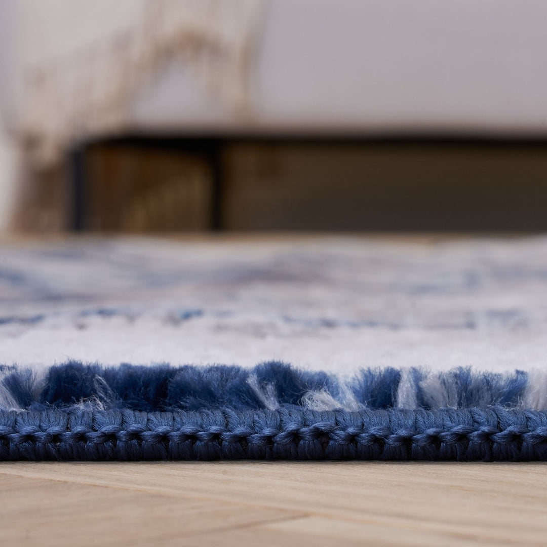 Close-up of a blue and white textured rug on a wooden floor.