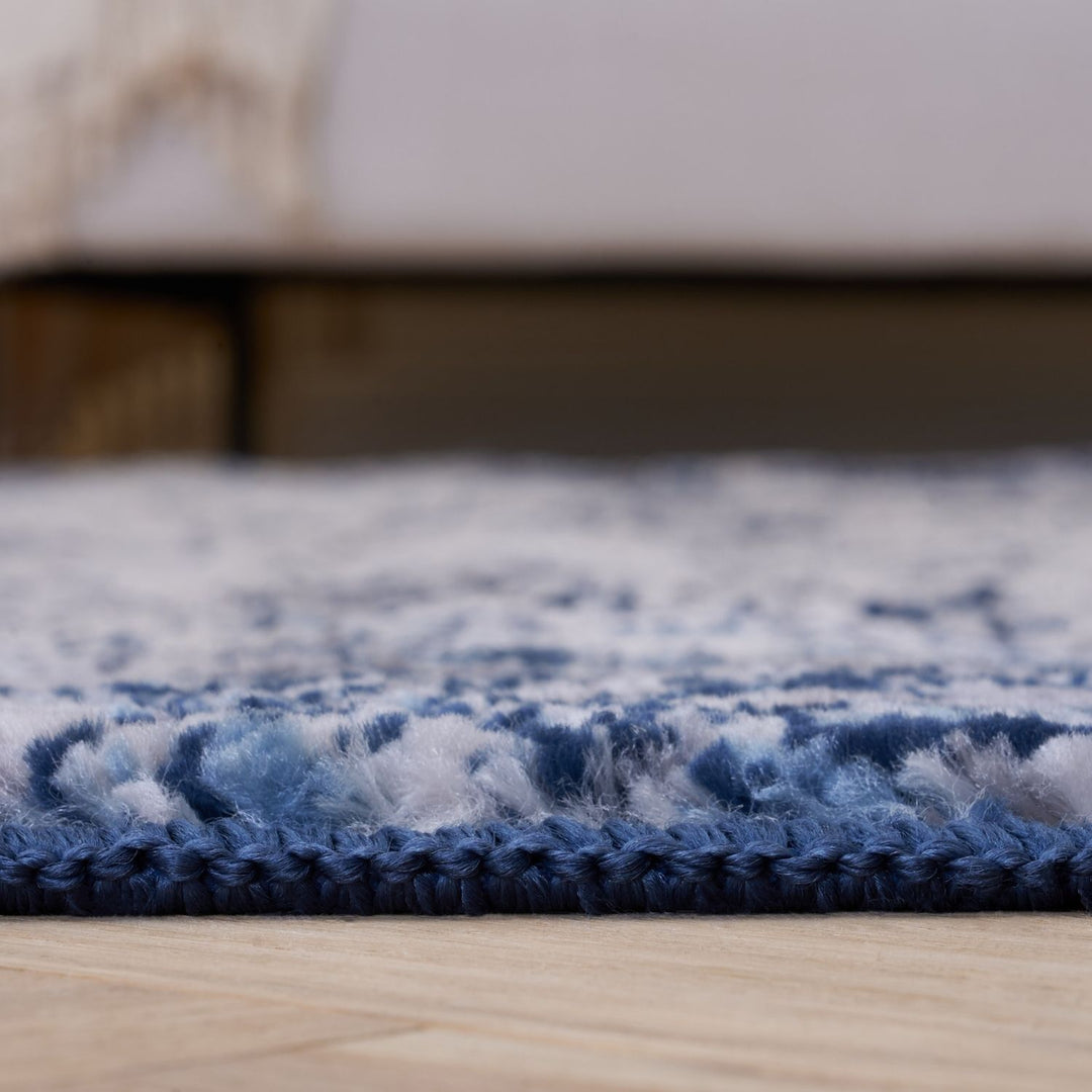 Close-up of a blue and white textured rug on a wooden floor.