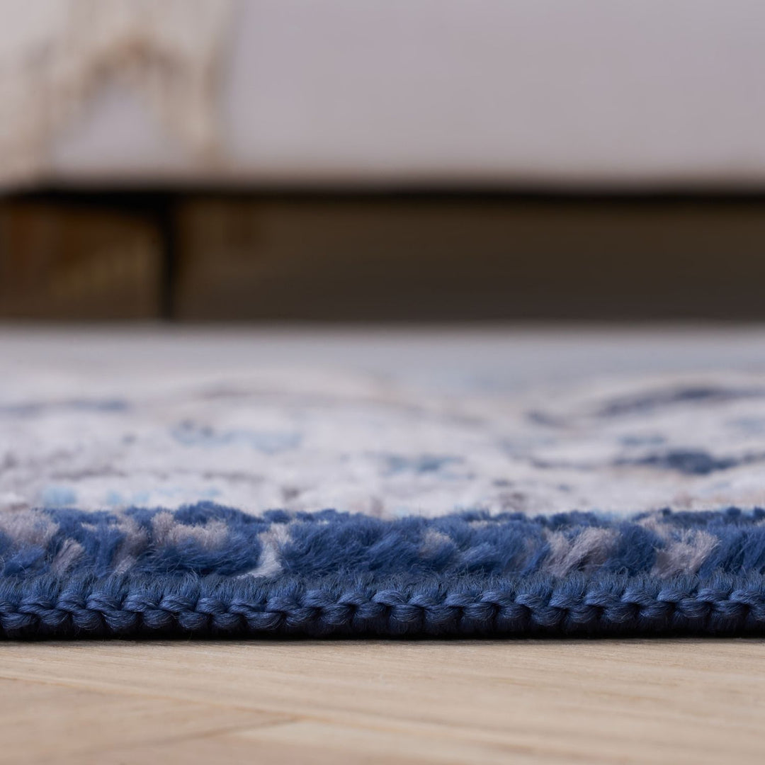 Close-up of a blue and white patterned rug on a wooden floor.