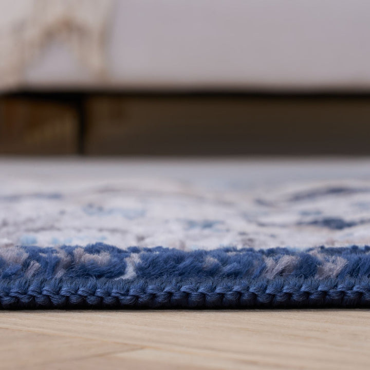 Close-up of a blue and white patterned rug on a wooden floor.