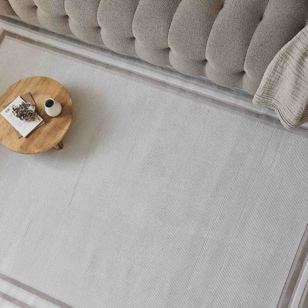 Beige rug with a decorative border in a living room setting.