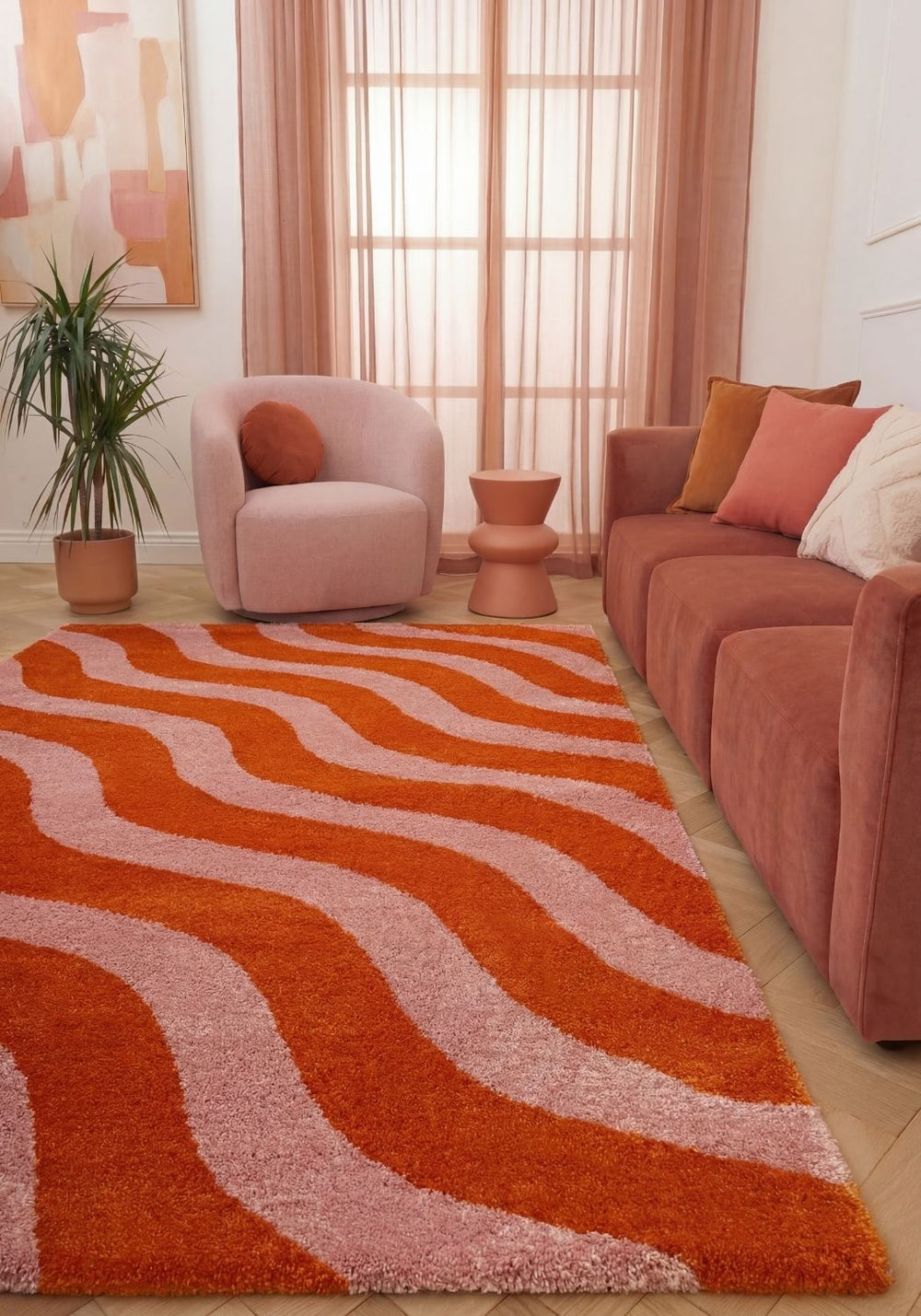 Living room with a wavy orange and pink rug, pink armchair, and sofa.