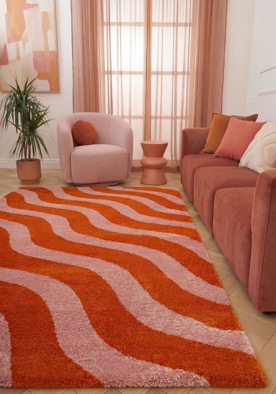 Living room with a wavy orange and pink rug, pink armchair, and sofa.