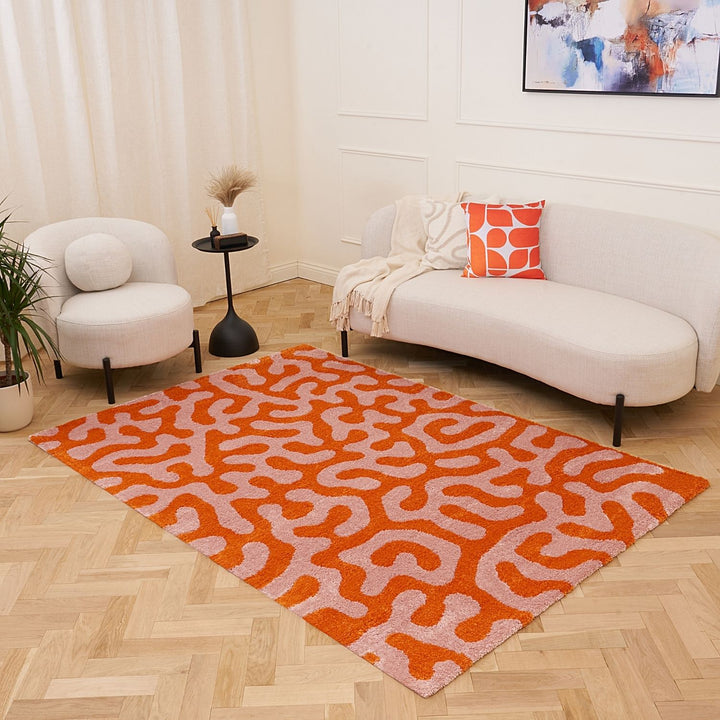 Living room with a white sofa, armchair, and orange patterned rug.