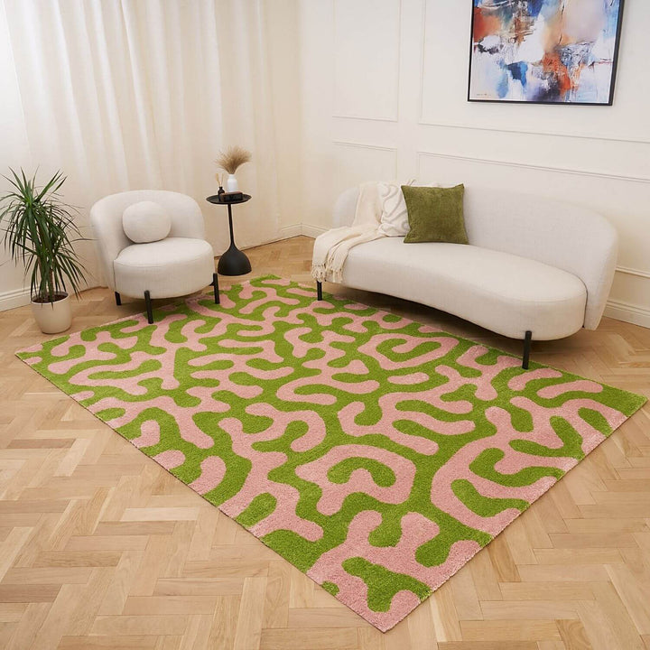 Living room with a green and pink patterned rug, white sofa, and abstract painting on the wall.
