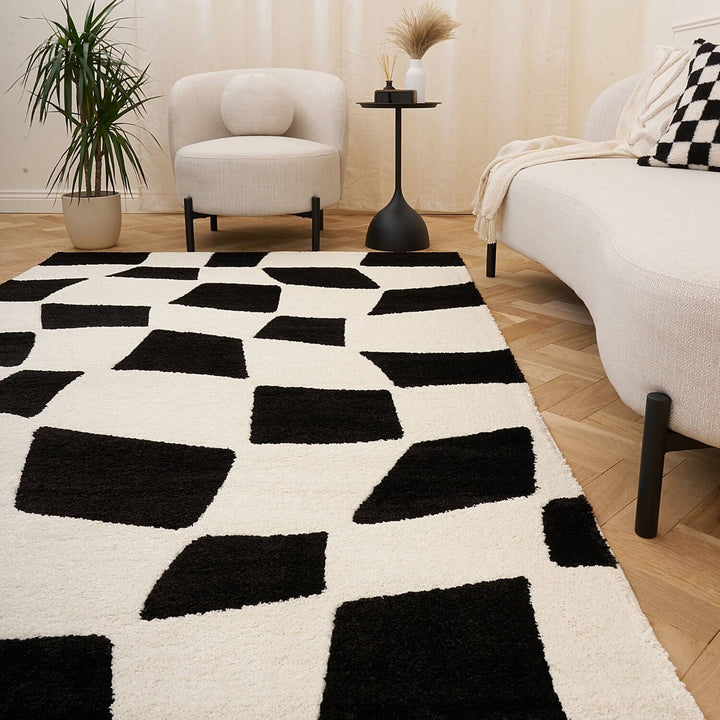 Living room with a black and white geometric rug, beige armchair, and side table.