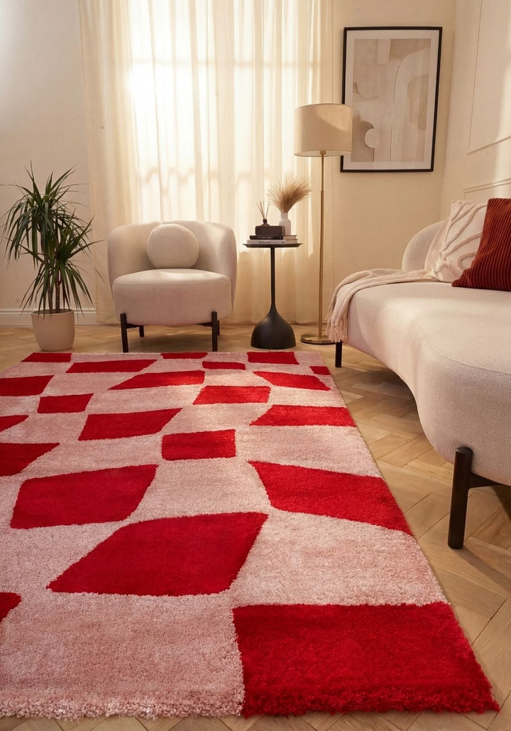 Living room with a red and white geometric patterned rug, white sofa, and armchair.
