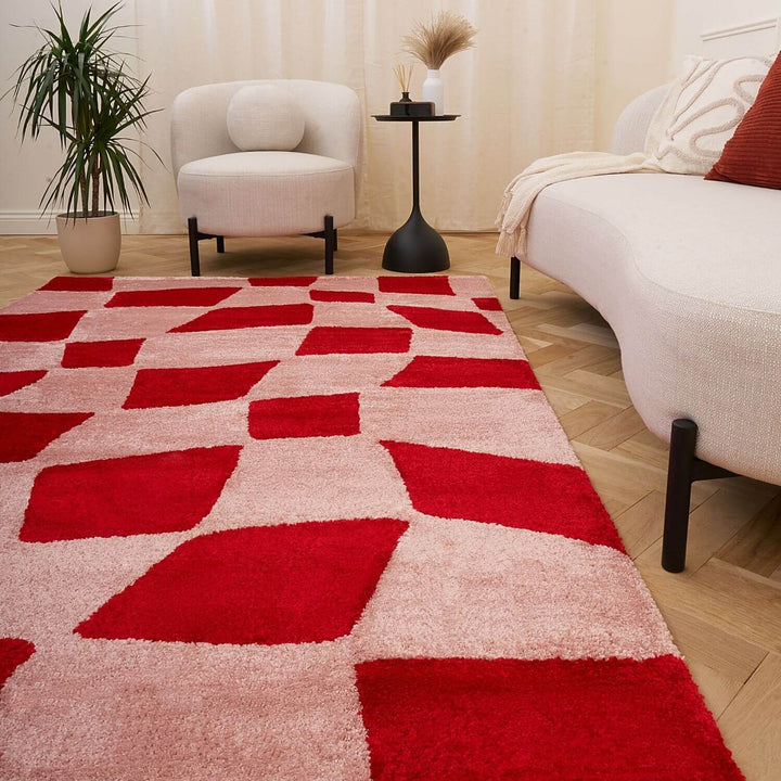 Red and beige patterned rug in a living room setting with a chair and plant.
