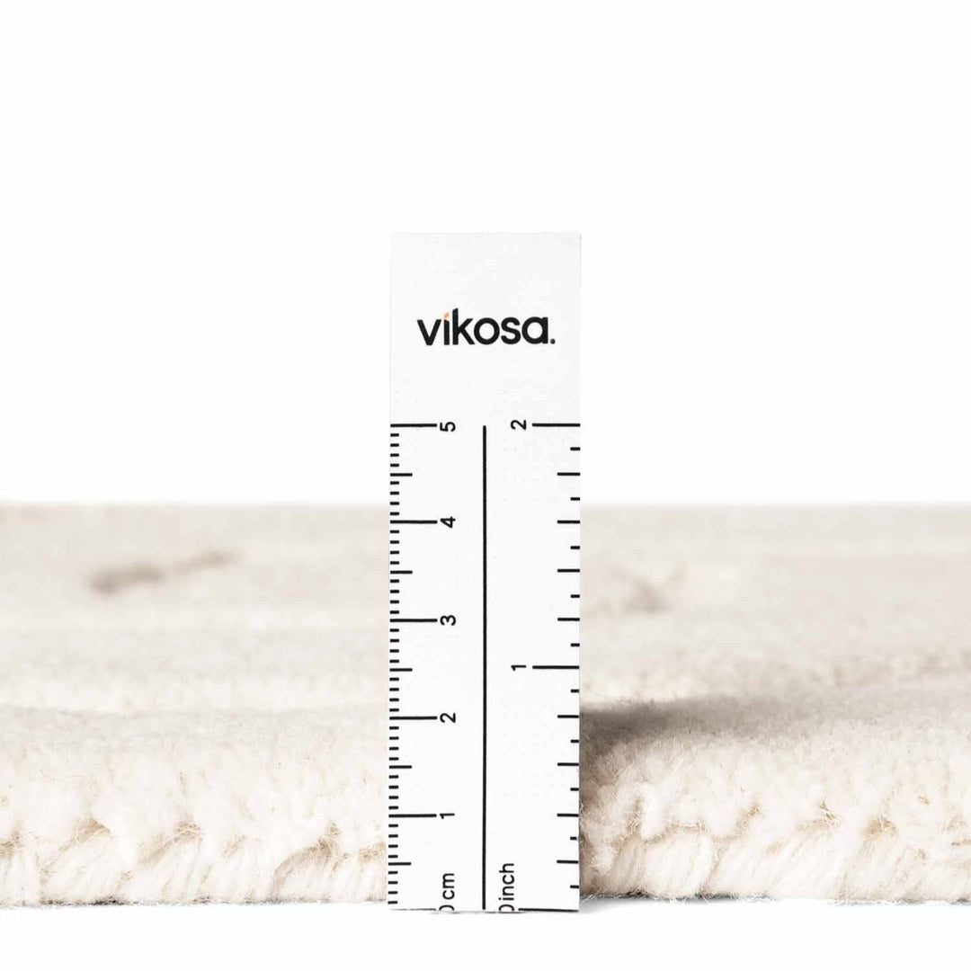 Close-up of a white marble surface with a ruler and 'vikosa' branding.