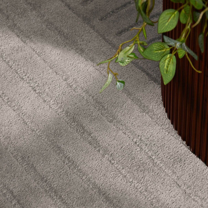 Gray textured rug with a plant on a wooden floor