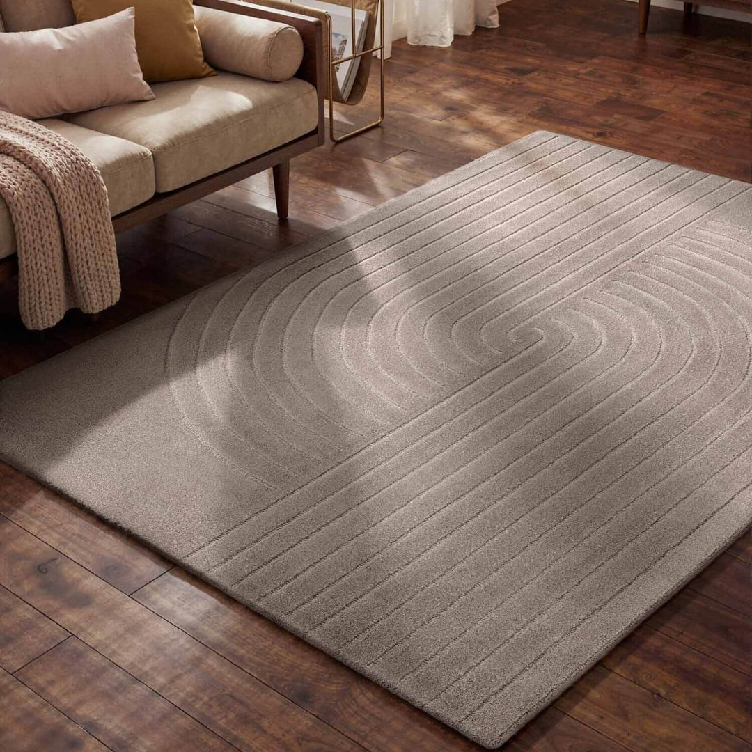 Gray area rug on a wooden floor with a beige sofa in the background