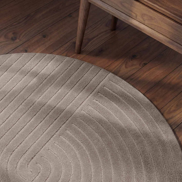 Round beige rug with a textured pattern on a wooden floor