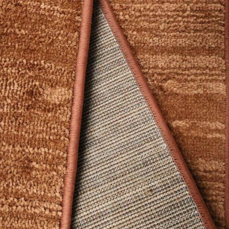 Close-up of Arlo Textured Rug showcasing soft striped design and sturdy backing in warm brown tones.