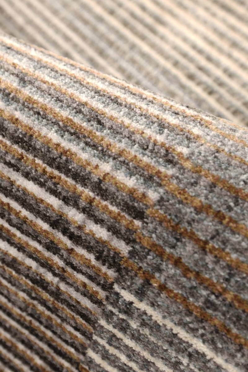 Close-up of Aspre Shades Lines Rug showcasing rich brown and gray stripes with high-low texture.