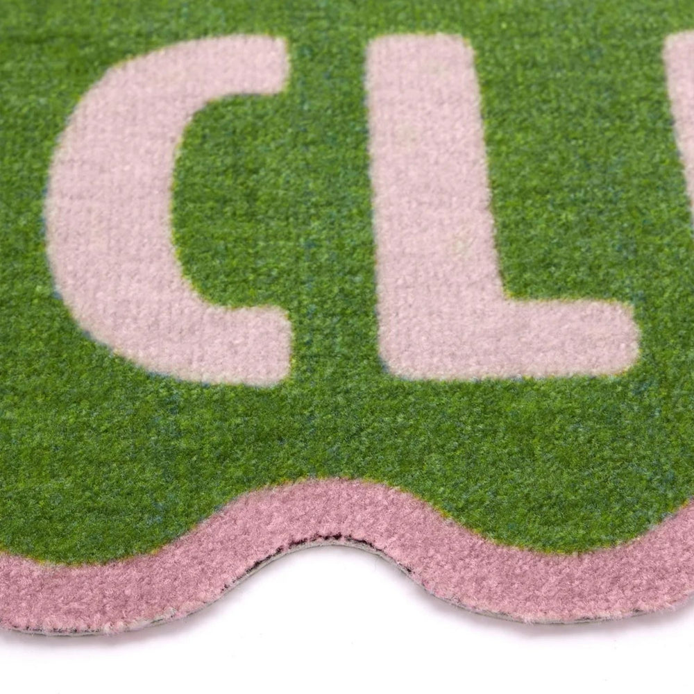 Close-up of a doormat with the word 'CLUB' on a green and pink background