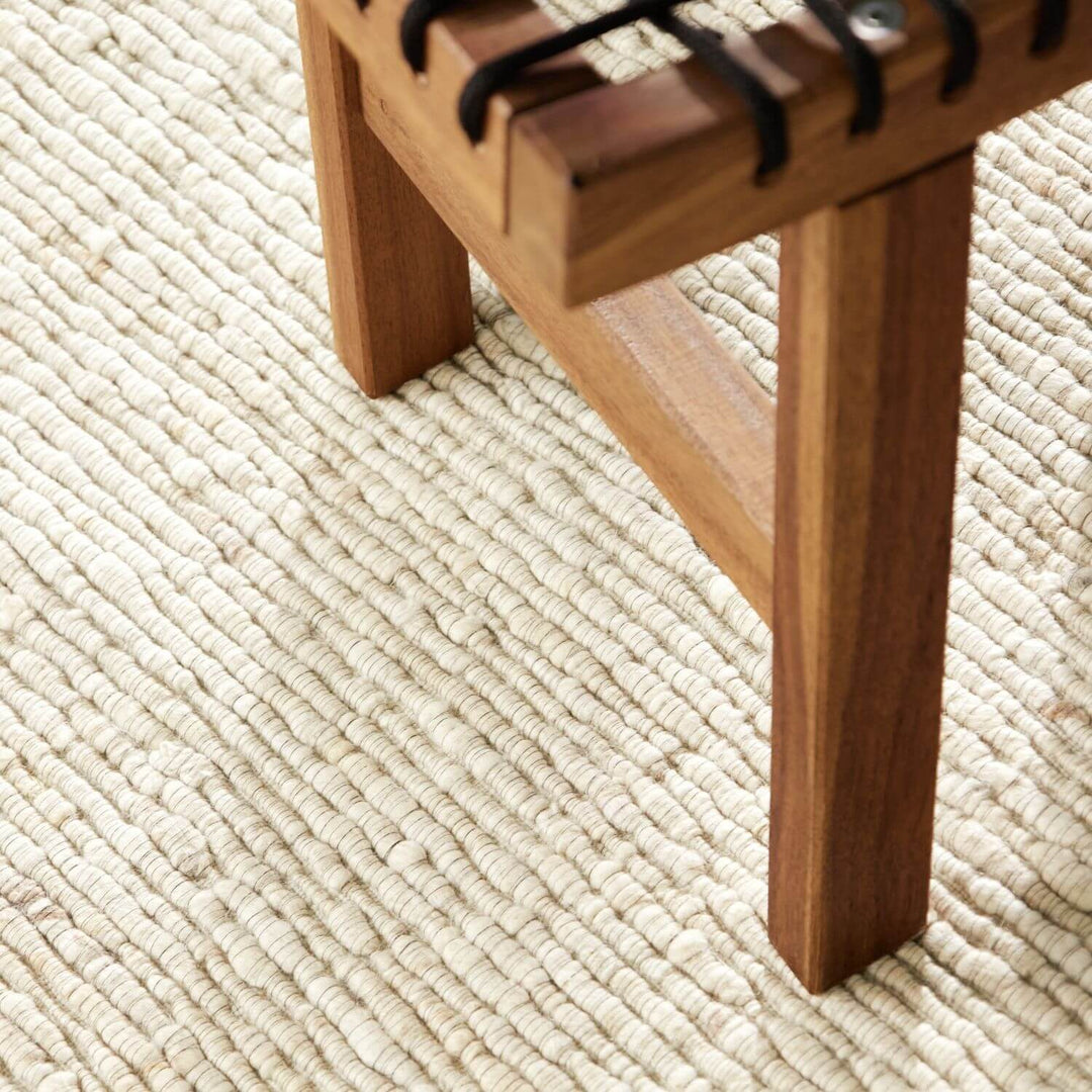 Wooden stool on a textured beige carpet