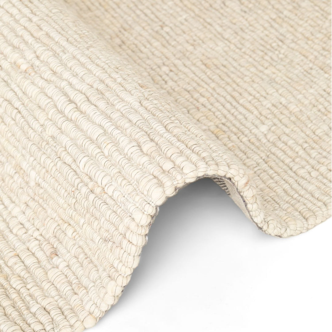Close-up of a textured beige rug corner on a white background