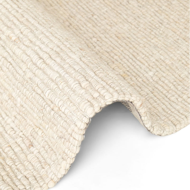 Close-up of a textured beige rug corner on a white background