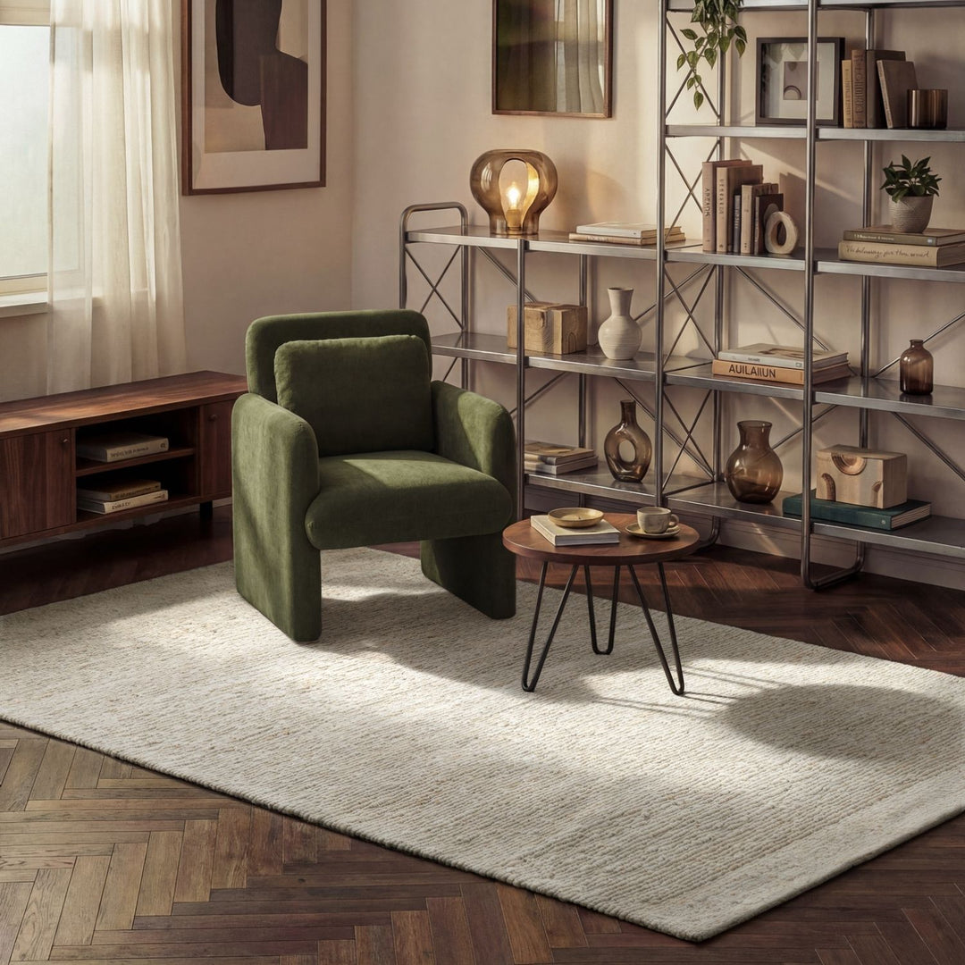 Green armchair in a living room with a bookshelf and table.