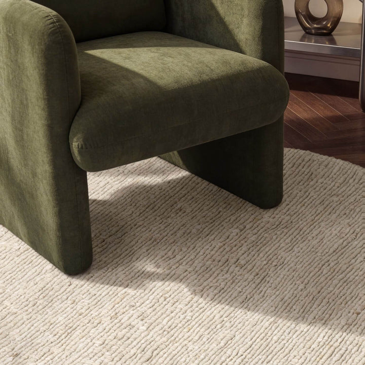 Green armchair on a textured rug with a blurred background