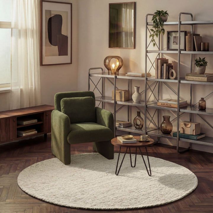 Modern living room with a green armchair, round coffee table, and metal shelving unit.