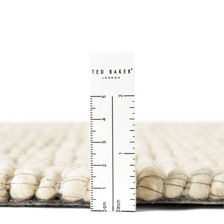 Close-up of a textured surface with a ruler and 'Ted Baker London' branding.