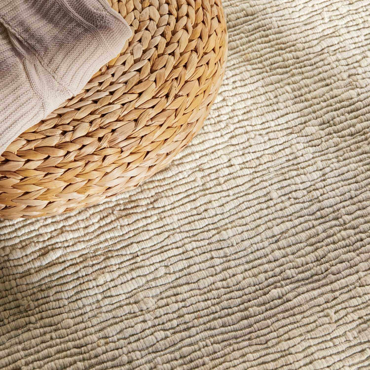 Close-up of textured beige carpet with a woven basket on top
