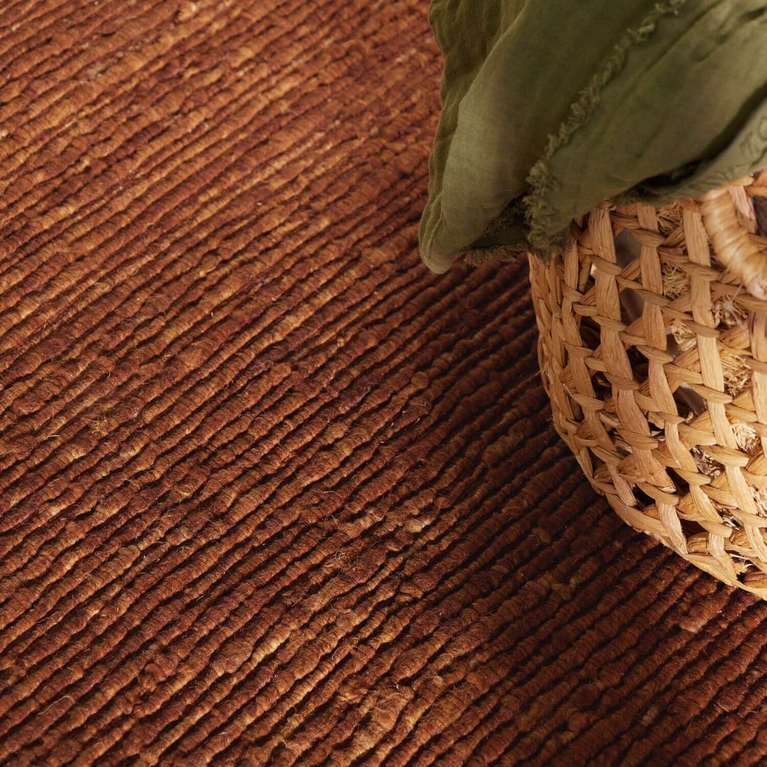 Brown textured carpet with a green fabric and wicker basket corner.