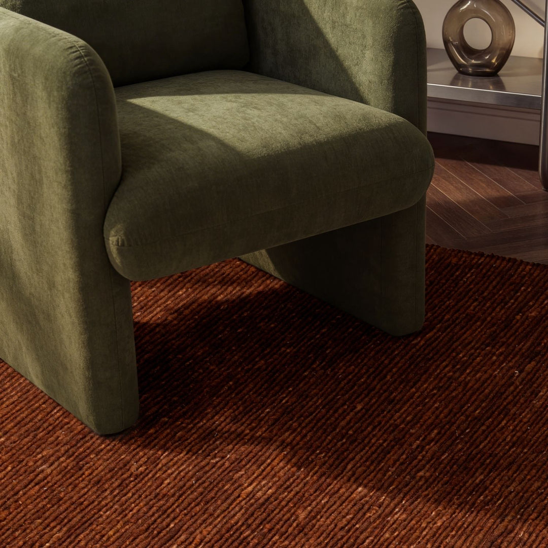 Green armchair on a brown rug in a room with a side table.