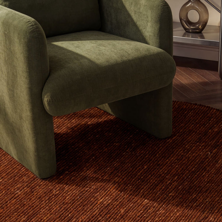 Green armchair on a brown rug with a blurred background