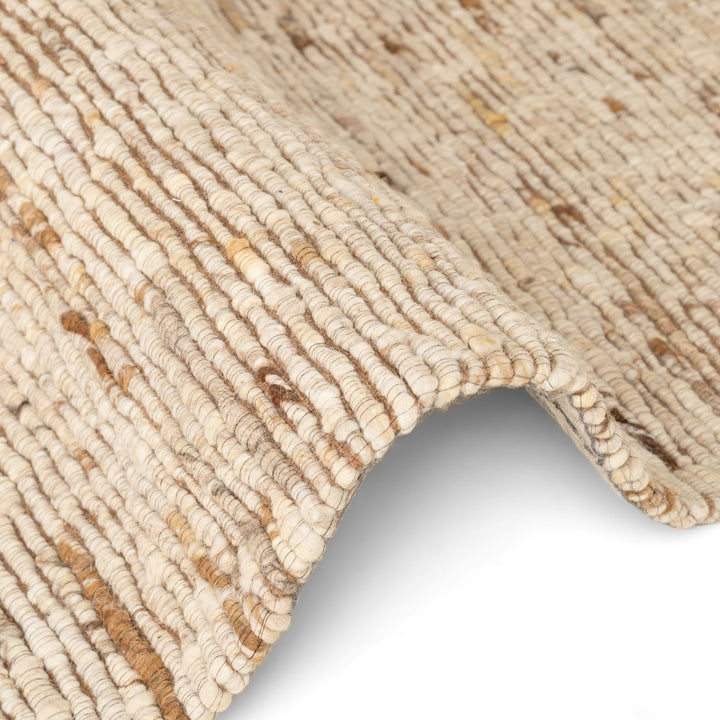 Close-up of a textured beige rug with a slight sheen on a white background